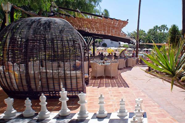 Außenbereich des Parque Tropical Hotels mit Tisch, Stühlen und einem großen Rattanball