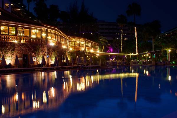 Nachtansicht des Parque Tropical Hotels mit beleuchtetem Swimmingpool und Gebäuden.