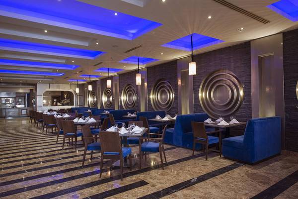 Innenbereich des Restaurants im Sunrise Arabian Beach Resort mit blauen Beleuchtung und Möbeln