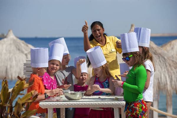 Gruppe von Kindern und einer Frau mit Kochmütze am Strand des Sunrise Arabian Beach Resorts