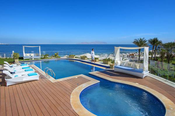 Außenpoolbereich des Sunrise Arabian Beach Resorts mit Loungeliegen und Blick auf das Meer.