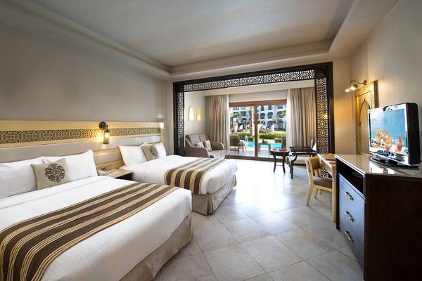 Doppelzimmer im Sunrise Arabian Beach Resort mit zwei Betten und Blick auf den Pool.