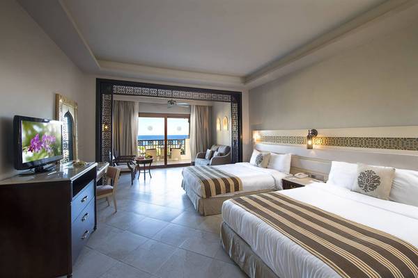 Zwei Betten in einem Hotelzimmer mit Meerblick, Fernseher und Möbeln.