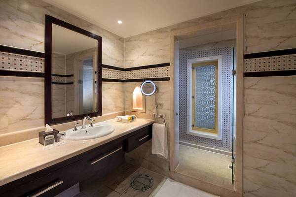 Badezimmer mit Marmorwänden, großer Spiegel und Glasdusche.
