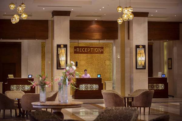 Reception Bereich von Sunrise Arabian Beach Resort mit Mann am Schalter und Blumenvasen.