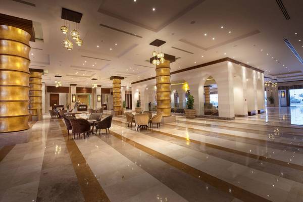 Lobby des Sunrise Arabian Beach Resorts mit goldenen Säulen und Möbeln.