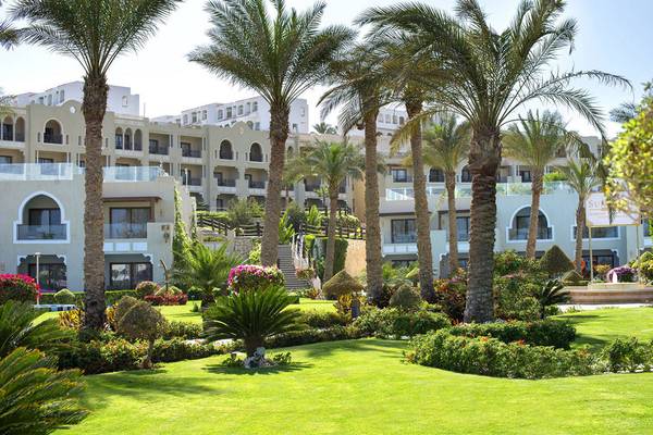 Außenbereich des Sunrise Arabian Beach Resorts mit grünem Rasen und Palmen.