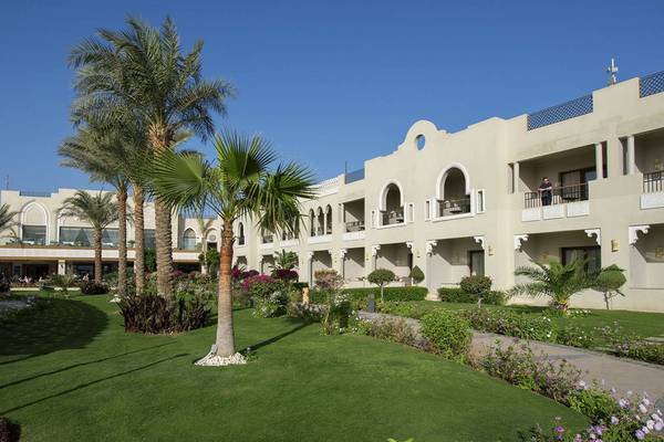 Außenansicht des Sunrise Arabian Beach Resorts mit gepflegtem Rasen und Palmen