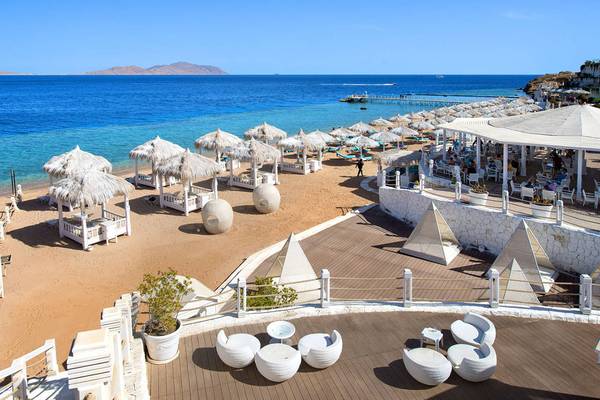 Aussicht auf das Sunrise Arabian Beach Resort mit Strand, Sonnenliegen und Blick auf das Meer.