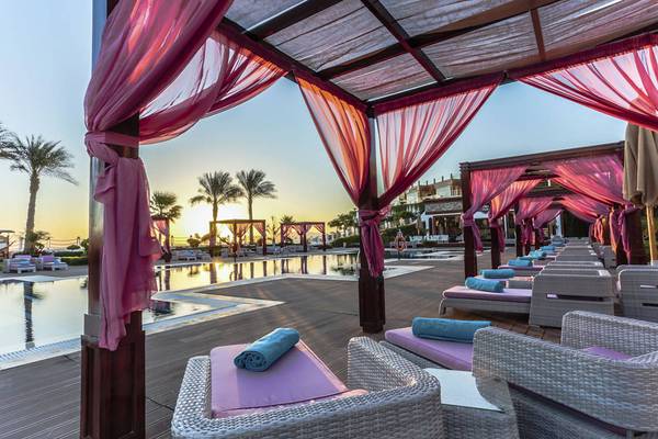 Sonnenuntergang am arabischen Strand Resort mit Lounge-Sesseln und roten Vorhängen.
