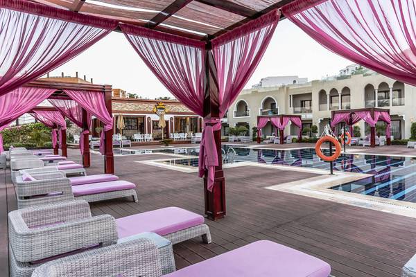 Poolbereich im Sunrise Arabian Beach Resort mit Lounge-Sesseln und pinken Vorhängen
