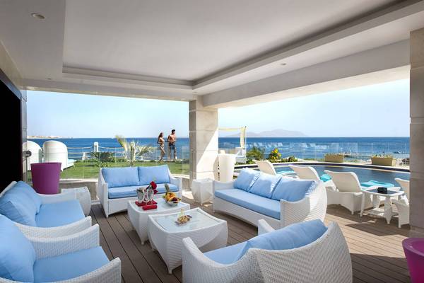 Terrasse mit Meerblick im Sunrise Arabian Beach Resort mit weißen Möbeln und zwei Personen, die den Ausblick genießen.