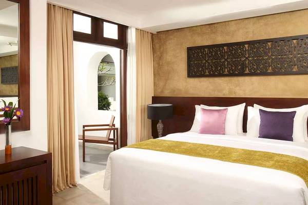 Ein elegantes Hotelzimmer im Avani Kalutara Resort mit einem Bett, Kissen und einem Lampenschirm.