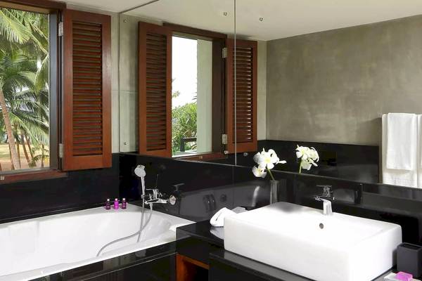 Badezimmer im Avani Kalutara Resort mit Badewanne, Waschbecken und Fenstern.