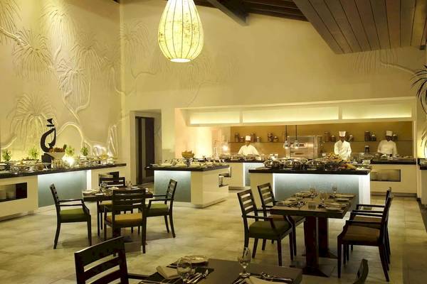 Innenansicht des Restaurants im Avani Kalutara Resort mit gedeckten Tischen und Köchen, die hinter der Theke stehen.