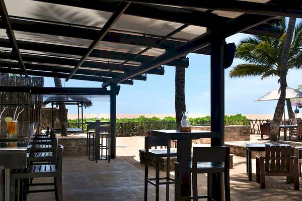 Außenbereich des Avani Kalutara Resorts mit Tischen, Stühlen und Blick auf den Strand.