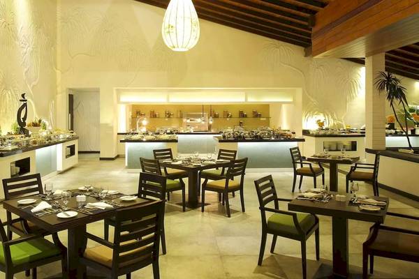 Innenbereich des Restaurants im Avani Kalutara Resort mit Tisch und Stühlen, Buffet und Palmenmotiven.