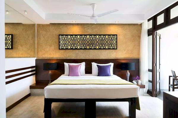 Bett im Zimmer des Avani Kalutara Resorts mit goldenen Wänden und dekorativem Wandbild