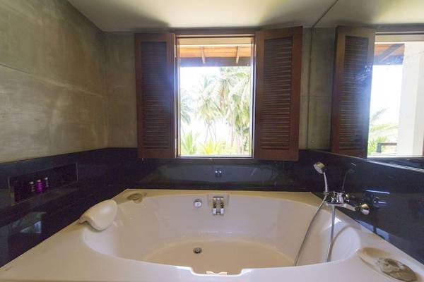 Badezimmer im Avani Kalutara Resort Hotel mit Badewanne und Ausblick auf Palmen