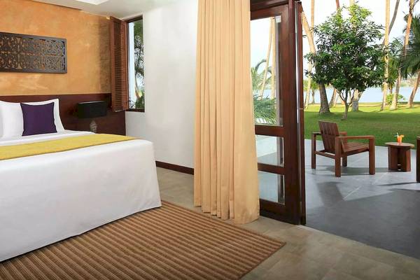 Innenansicht eines Zimmers im Avani Kalutara Resort mit Blick auf eine Terrasse und einen Garten.