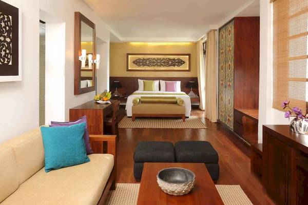 Innenansicht eines Hotelzimmers im Avani Kalutara Resort mit einem Bett, Sofa, Tisch und Dekor.
