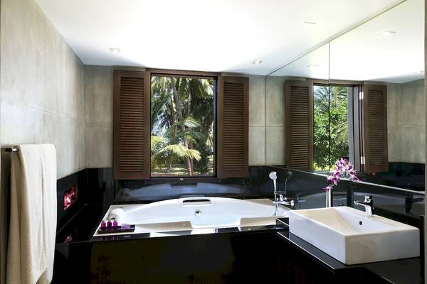 Badezimmer im Avani Kalutara Resort mit Badewanne und Ausblick auf Palmen.