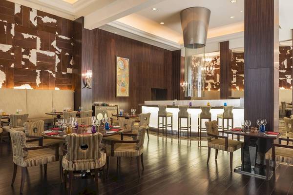 Innenbereich des Sheraton Oman Hotels mit Tisch, Stühlen und Bar.