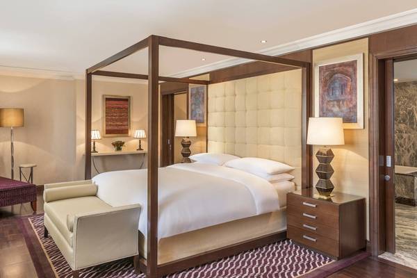 Schlafzimmer im Sheraton Oman Hotel mit Himmelbett, Kissen und Lampen.