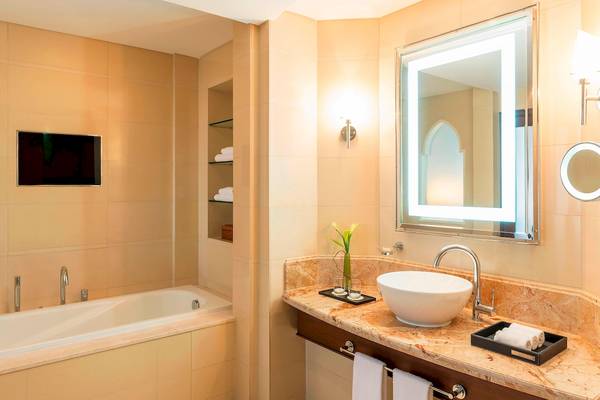 Badezimmer im Sheraton Oman mit Badewanne, Waschbecken und Spiegel