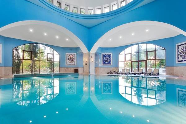Ein blauer Swimmingpool im Swandor Hotels & Resorts Topkapi Palace mit Lounge-Stuhlreihen.