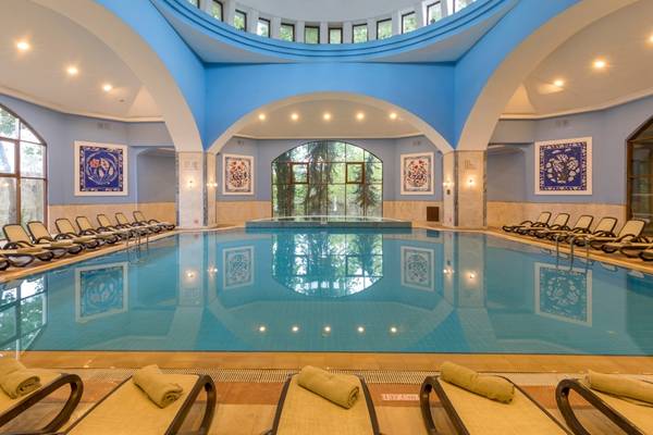 Innenansicht des Schwimmbads im Swandor Hotels & Resorts Topkapi Palace, mit blauen Wänden und Liegestühlen.