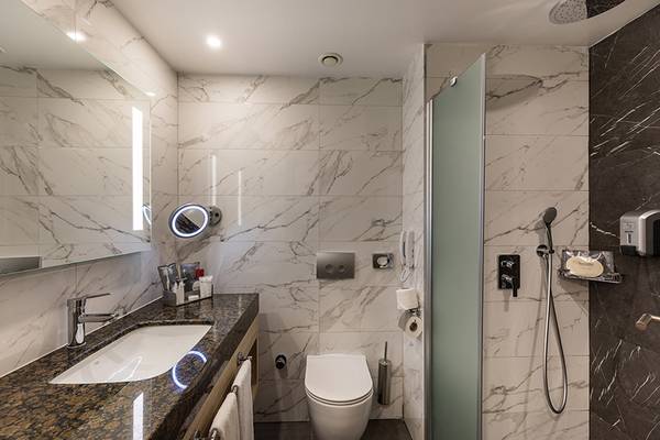 Badezimmer des Swandor Hotels & Resorts Topkapi Palace mit Marmorwänden und einer Glasdusche.