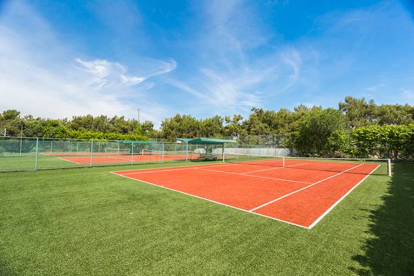 Tennisplatz im Defne Kumul Deluxe Hotel mit grünem Rasen und roten Spielflächen.