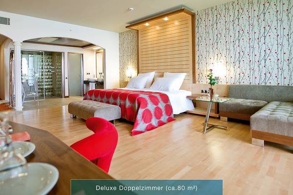 Defne Kumul Deluxe Doppelzimmer mit einem Bett, Sofa, Tisch und roter Dekoration.