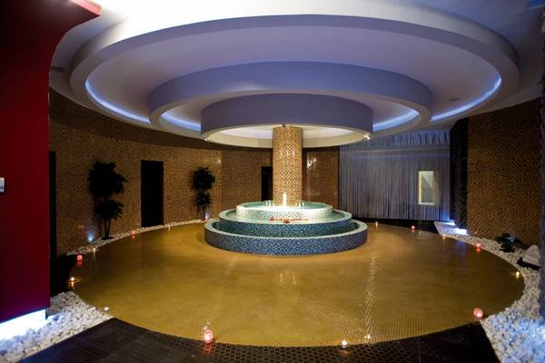 Innenbereich des Defne Kumul Deluxe Hotels mit einem zentralen Brunnen und umgebenden Kerzen.