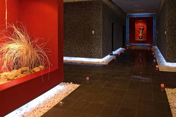 Spa-Flur im Defne Kumul Deluxe Hotel mit roten Wänden, schwarzen Fliesen und beleuchteten Steinen.