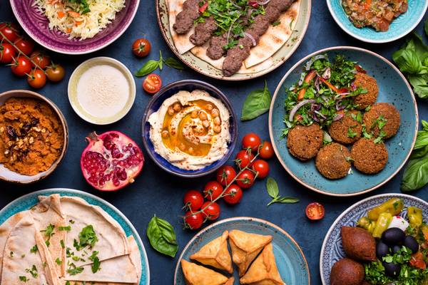 Orientalische Gerichte wie Falafel, Hummus und verschiedene Salate auf einem blauen Hintergrund.