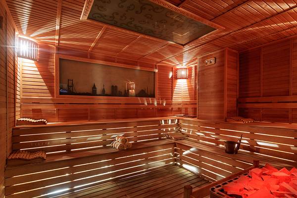 Innenansicht der Sauna im Kristall Waterworld Aqua Collection Hotel mit Holzwänden und Decken, Sitzbänken und einem Bild an der Wand.