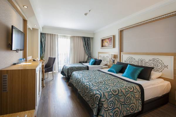 Innenansicht eines Doppelzimmers im Crystal Waterworld Aqua Collection Hotel mit zwei Betten, Fernseher, und Wohnzimmerbereich.