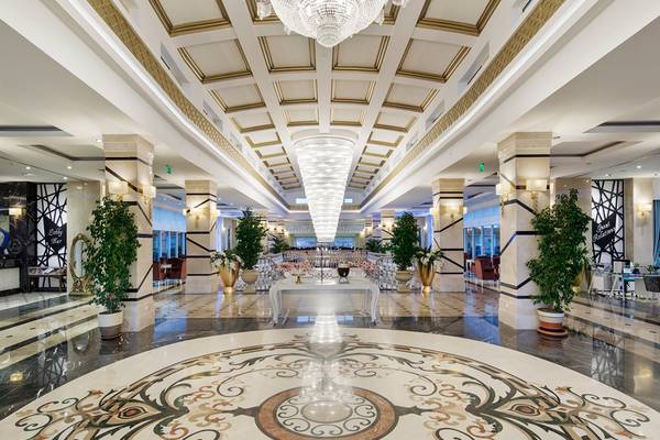 Hotellobby mit großen Kristallleuchten und einem kunstvollen Marmorbodendesign.
