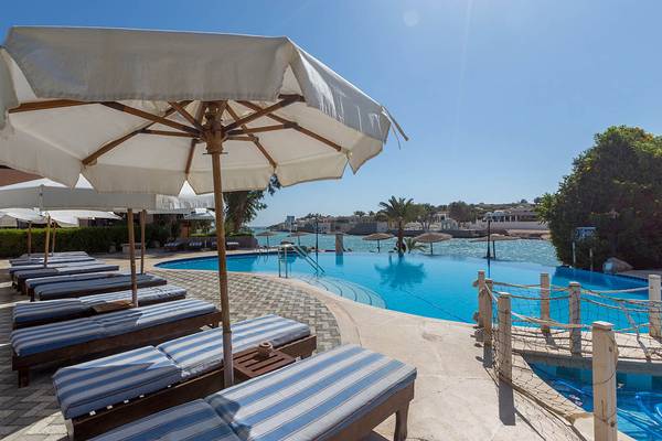 Am Poolbereich des Sultan Bey Resorts stehen Liegestühle und Sonnenschirme unter dem blauen Himmel.