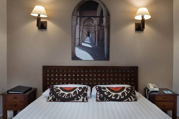 Bett im Hotelzimmer des Sultan Bey Resorts mit architektonischem Wandbild.