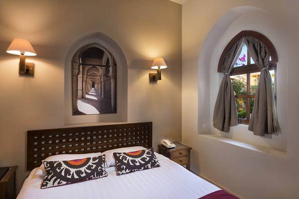 Zimmer im Sultan Bey Resort mit Bett, zwei kunstvollen Kissen und Wanddekoration.