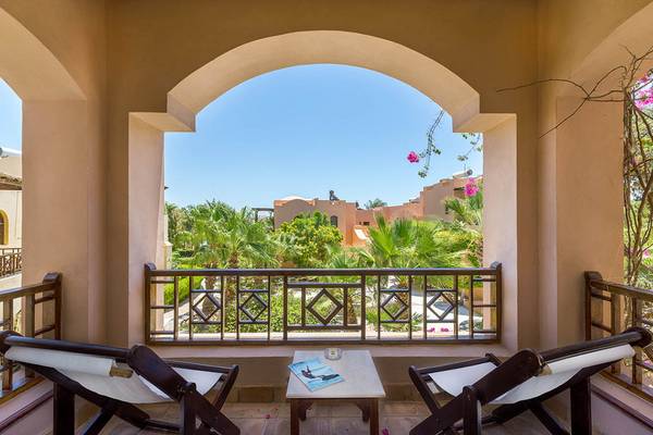 Balkon des Sultan Bey Resorts mit zwei Sitzen und Ausblick auf eine tropische Landschaft.