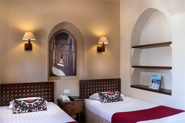 Zwei Betten im Zimmer des Sultan Bey Resorts mit Wandlampen und einer Wandmalerei.