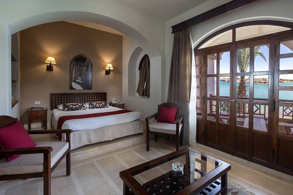 Hotelzimmer im Sultan Bey Resort mit großem Bett, Sitzgelegenheiten und Balkon mit Meerblick.
