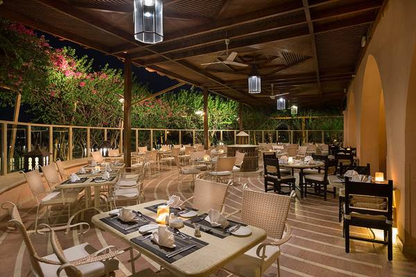 Außenrestaurant des Sultan Bey Resorts bei Nacht mit runden Tischen und Stühlen.