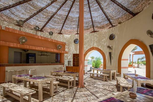Innenansicht des Essbereichs im Sultan Bey Resort mit Tischen, Bänken und einem gewölbten Dach.