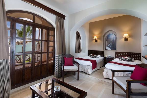 Zimmer im Sultan Bey Resort mit Blick auf das Meer und zwei Betten, neben einem Tisch und Stühlen.
