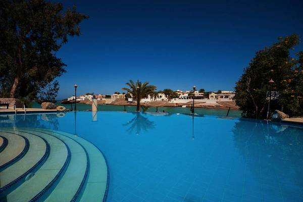 Außenpool des Sultan Bey Resorts mit blauem Wasser und umliegenden Bäumen.